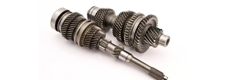 Three machined stainless steel gear shafts on white