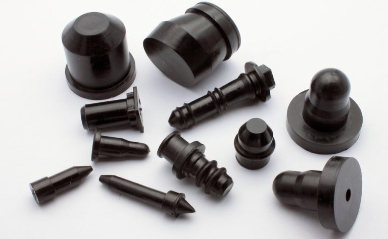 Black plastic CNC machined parts scattered on white