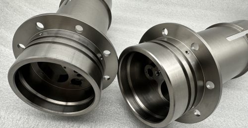Two titanium machined cylindrical parts with flanges
