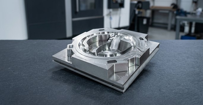 H13 tool steel mold core insert on dark worktable