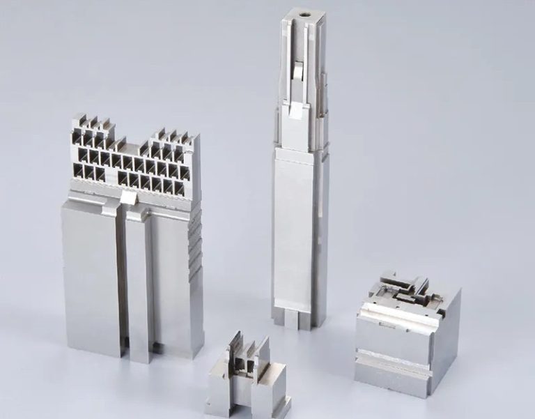 Four precision machined metal parts on white background