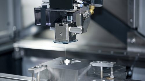 Wire cutting machine EDM head feeding thin wire to cut metal part